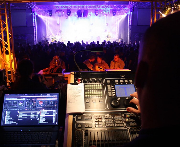 Blick auf eine Bühne auf der eine Band spielt, während viele Leute davor stehen