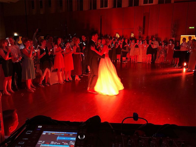 Braut und Bräutigam tanzen in rotem Licht, umringt von einer großen Zuschauerschaft